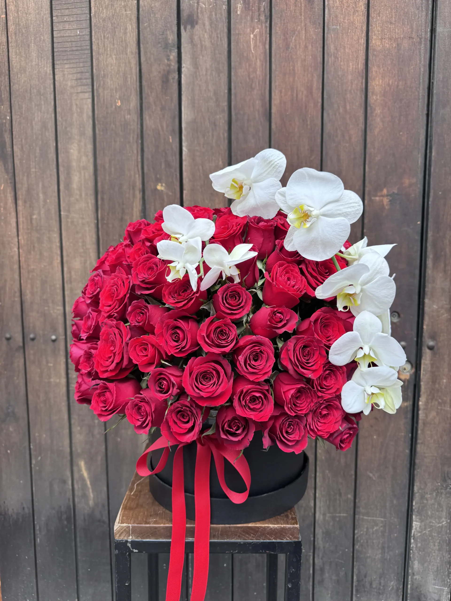 caja elegante de rosas rojas con orquideas blancas